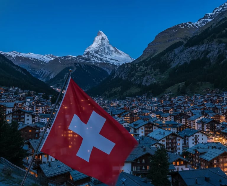 A Swiss flag waving in the foreground, with the iconic Matterhorn mountain and the snow-covered vill