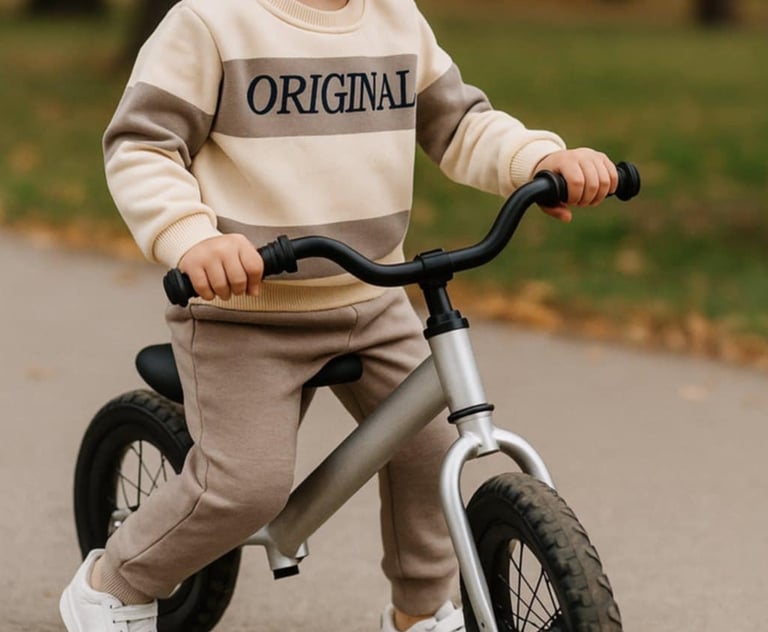 vaikas apsirengęs laisvalaikio kostiumėliu važiuoja dviračiu