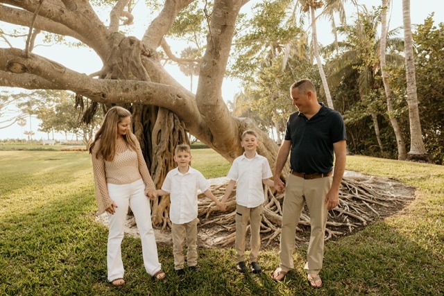 a family of four standing in front of a tree
