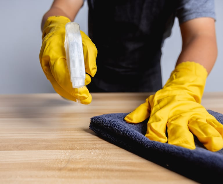une personne portant des gants jaunes nettoyant une table a l'aide d'un chiffon d' un produit .