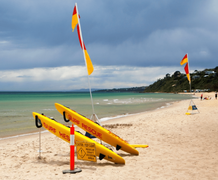 a surfboarder is sitting on the beach. Australina surf rescue beach