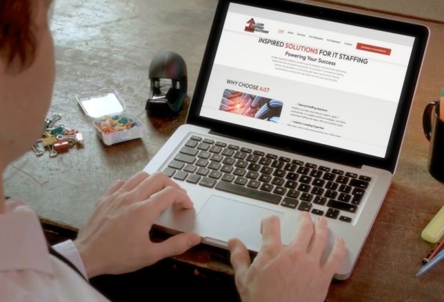 a man sitting at a desk with a laptop computer and a cell phone