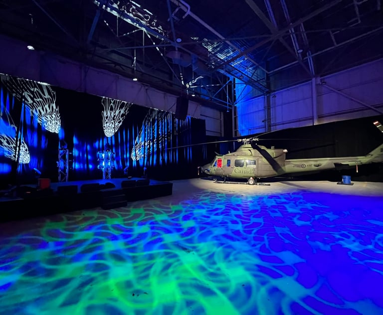Military helicopter in a large hangar with dramatic blue and green event lighting and projection mapping.
