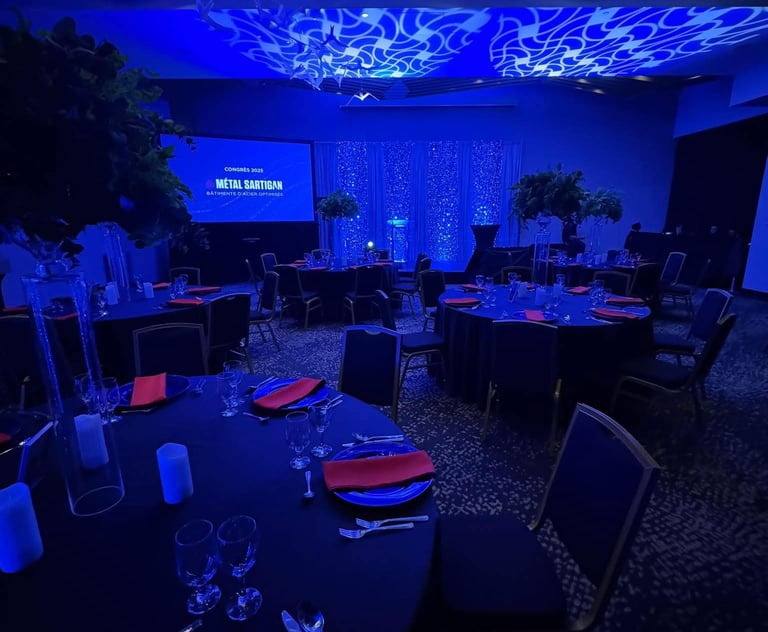 Elegant gala dinner venue with blue ambient lighting, round banquet tables, and floral centerpieces.