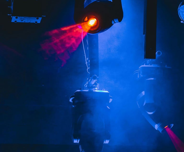 Professional stage lighting equipment projecting vibrant red laser beams through blue concert fog.