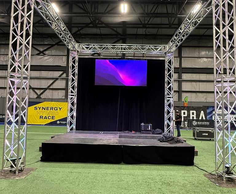 Professional portable event stage with silver aluminum truss system and LED screen on turf.