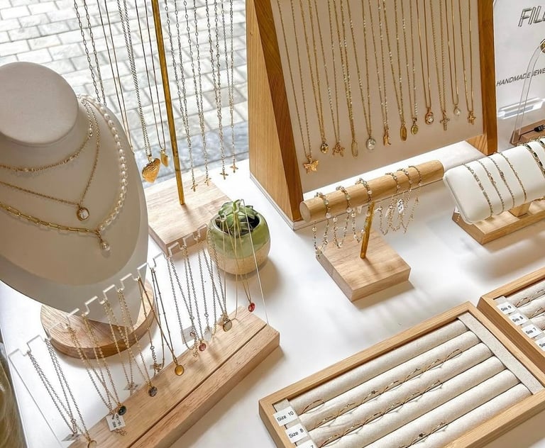 Collares, anillos y pulseras de oro colgando en un exhibidor de soportes de joyería de madera.