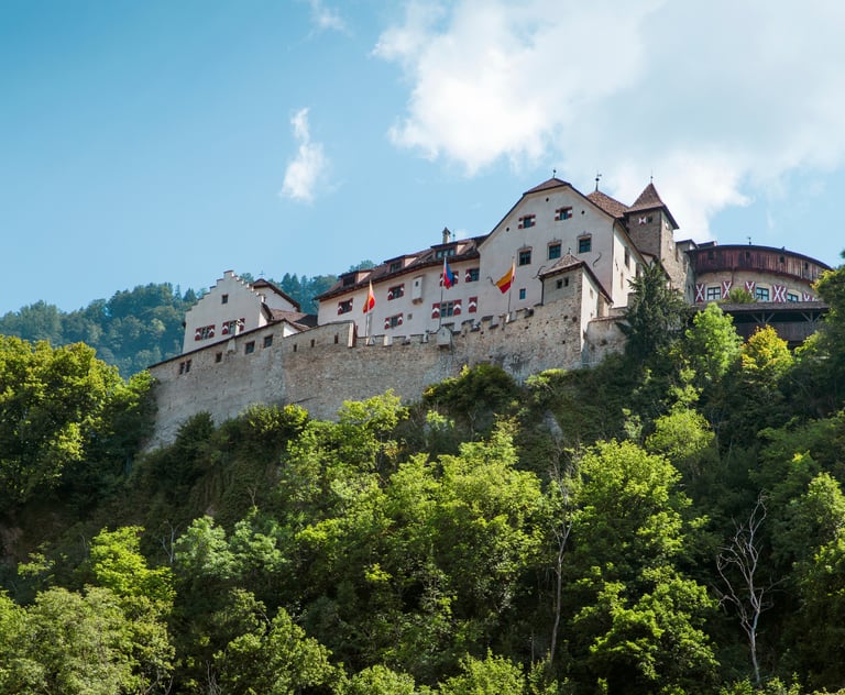 Majestic Vaduz Castle perched on a forested hilltop in Liechtenstein, with sunlit medieval walls, co