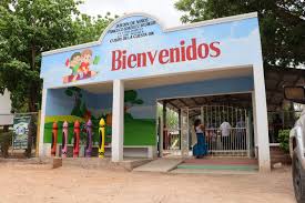 A colorful school entrance in Mexico featuring a Bienvenidos sign and giant crayon pillars.