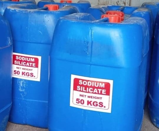 a group of blue plastic barrels with red and white labels filled with liquid sodium silicate