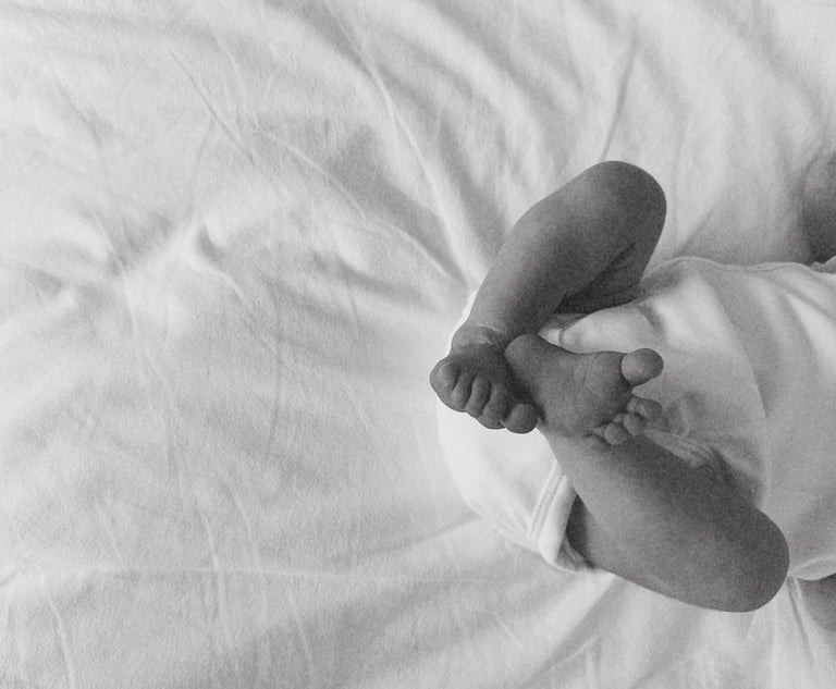 bas du corps d'un bebe allonger sur un lit avec des draps blancs