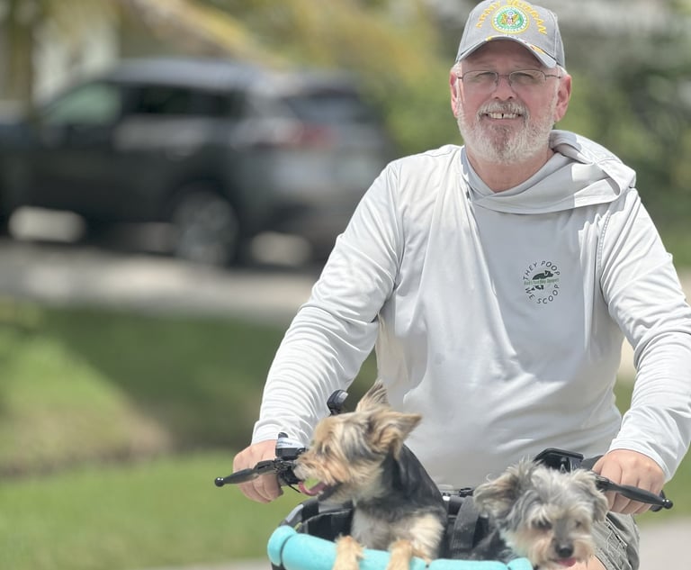 Robert smiling while riding a bicycle with two dogs in a basket