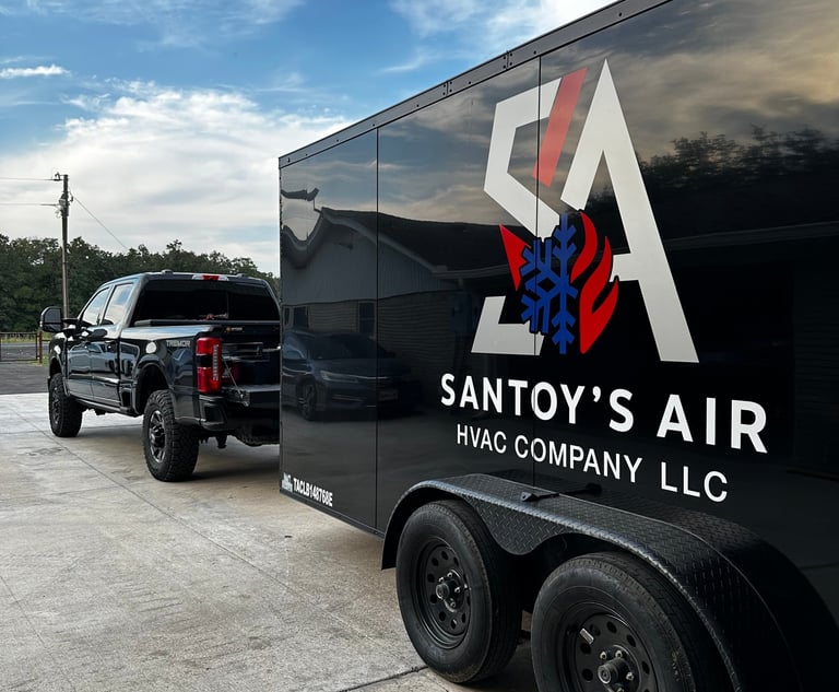 A black Santoy's Air HVAC company truck and service trailer parked on a driveway under a blue sky.