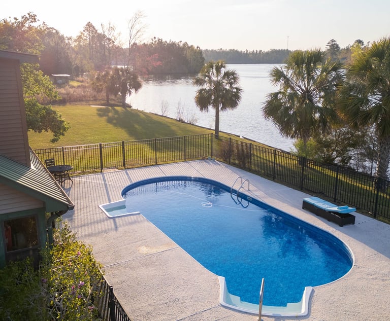 a pool with a fenced in area with a bench and chairs