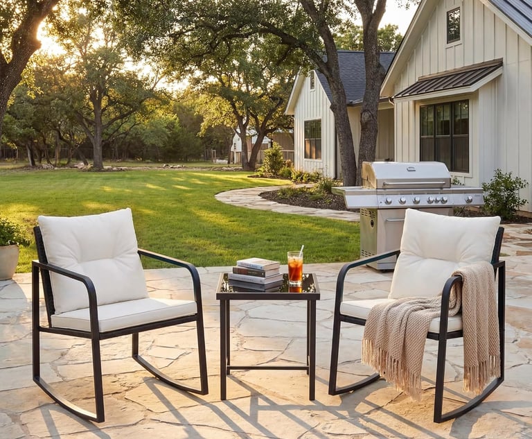 Outdoor patio set with two black metal rocking chairs and a side table on a stone terrace.