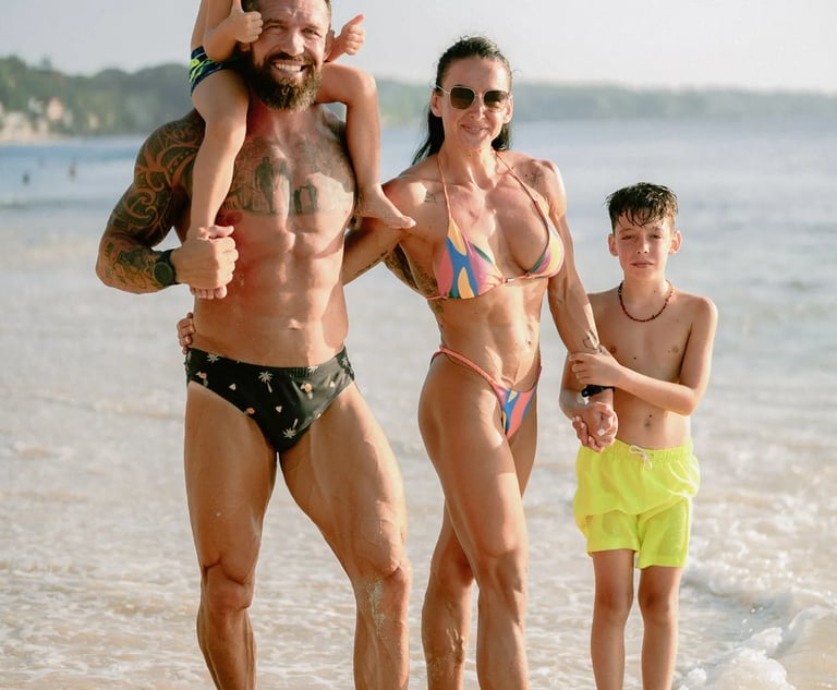 Family walking together through shallow ocean water during a sunset family photography session at Dreamland Beach Bali.