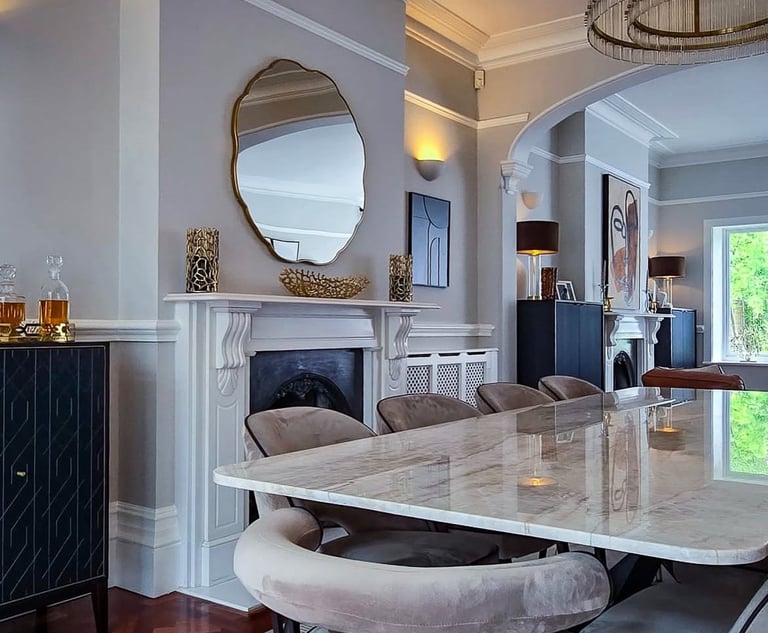 Sleek dining area with a marble table, velvet chairs, and modern chandeliers in an open-plan space