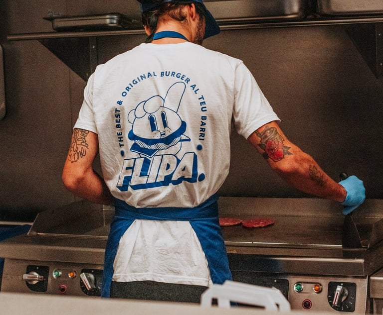 Cocinero de Flipa cocinando carne en la plancha con camiseta oficial de la marca