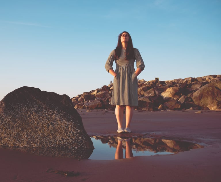 photo of woman looking up at the sky on a beach at sunset