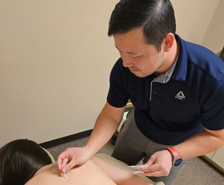 Dr. Xiong performing acupuncture treatment for back pain at Balance Naturopathic & Acupuncture.