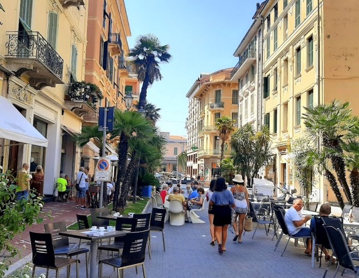 Rue animée de Bordighera, avec des restaurants, commerces et des personnes qui marchent
