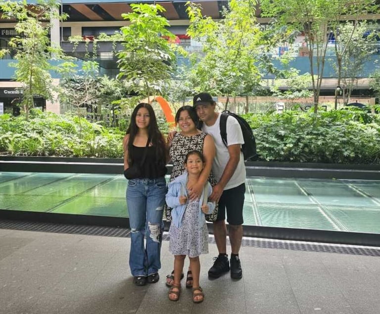A happy family posing together in a modern outdoor shopping center with lush green plants.