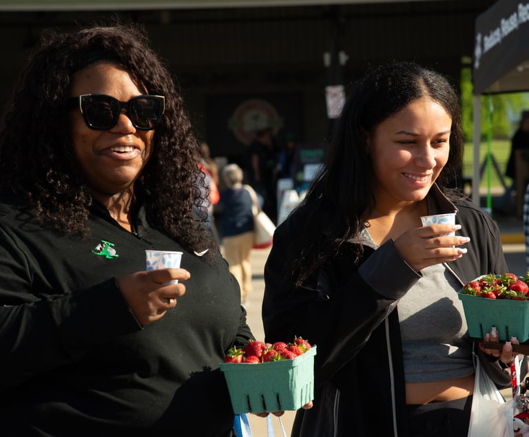 Two adults leaving the farmers market enjoying our bike-powered smoothies