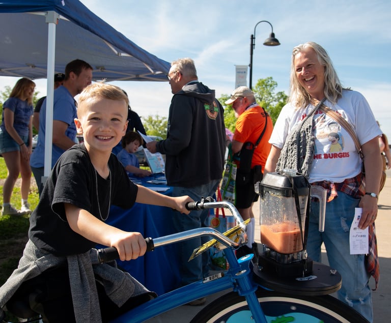 Child powering the blender bike with their adult nearby smiling