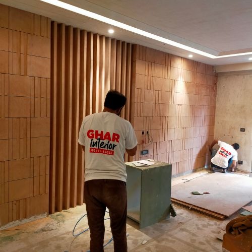 Professional carpenters installing a modern wooden wall panel design for a home interior renovation.