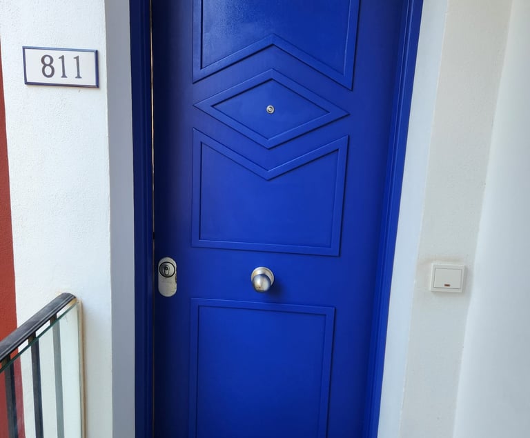 Modern vibrant blue front door with geometric paneling and silver hardware next to house number 811.