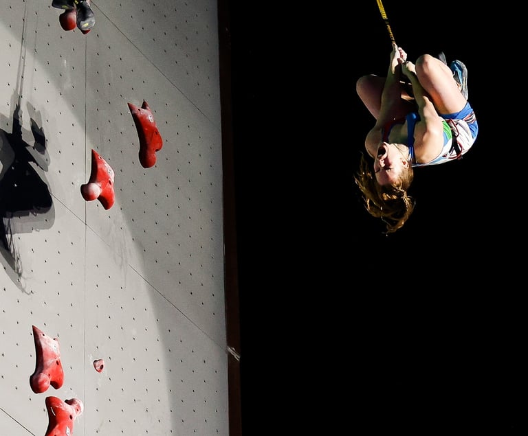 a woman is coming down from a speed climbing wall