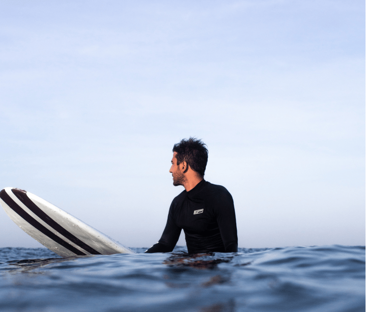 a man in a wetsuit is holding a surfboard