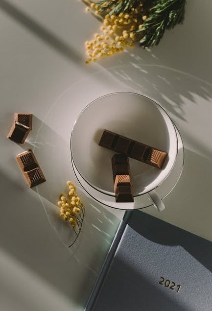 tea cup with chocolate pieces inside next to a 2021 journal