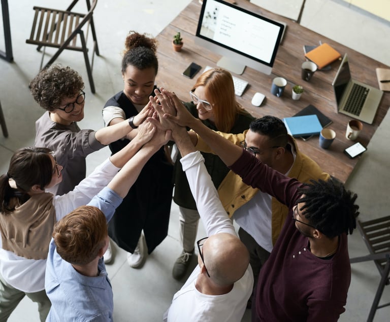 A group of people in an office, hands raised, ready to assist.