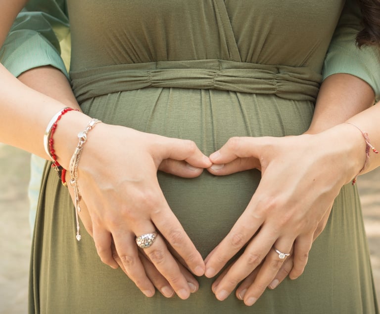 a pregnant woman in a green dress with her hands on her belly