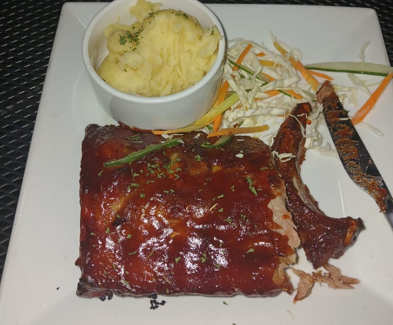 a plate of ribs and mashed potatoes