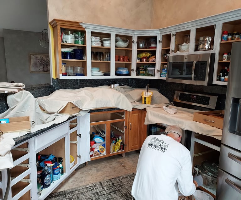 a man in white painting kitchen cabinets
