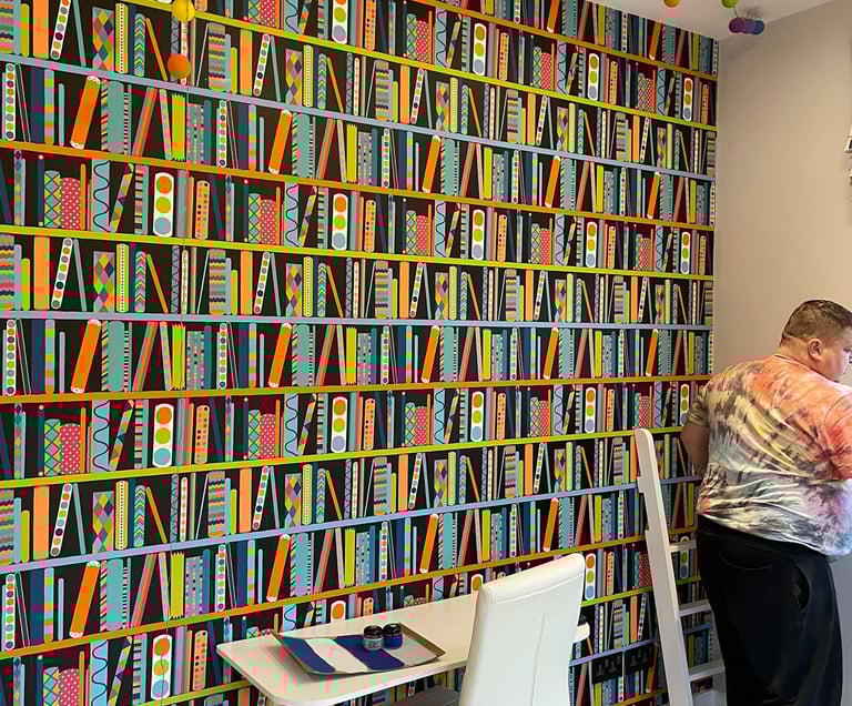 A wallpaper which depicts a colourful book shelf ideal for a young pre-teen unisex room