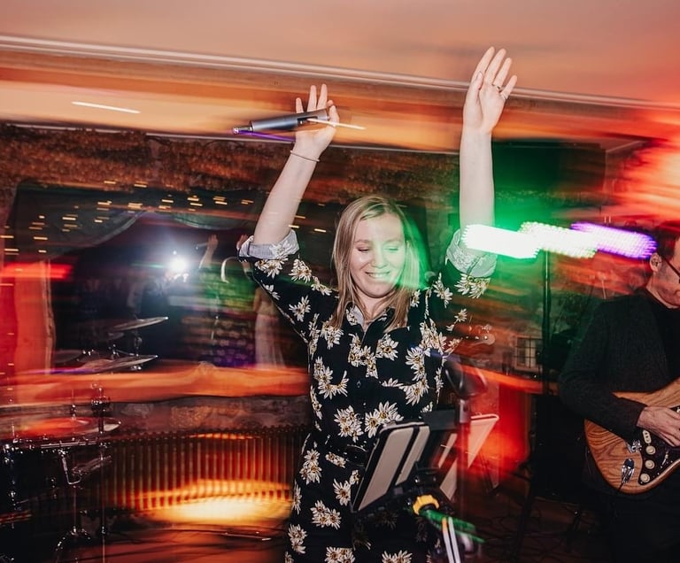 a woman in a floral jumpsuit dancing with a guitar at wedding party