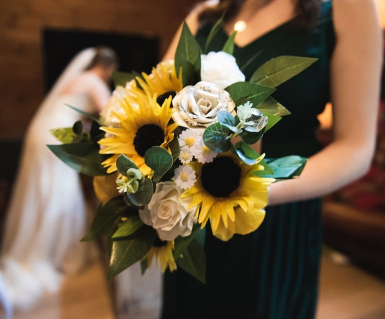 a woman in a green dress holding a bouquet of wedding flowers
