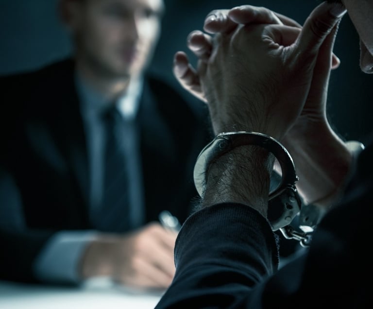 man in handcuffs talking to lawyer