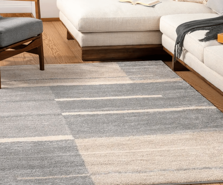 Modern gray and cream geometric area rug under a white sectional sofa in a bright living room.