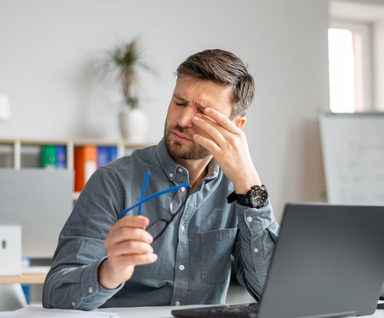 Man taking off his glasses and rubbing his eyes in pain