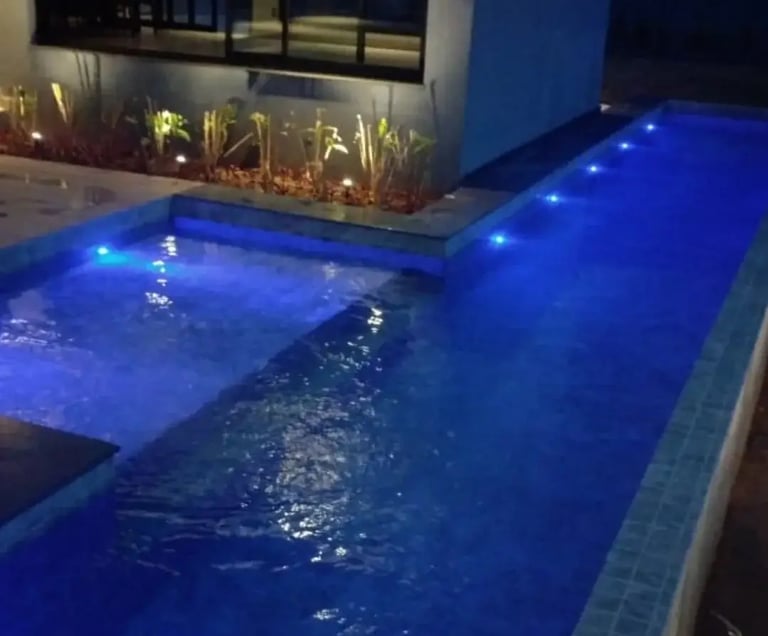 Pemandangan kolam renang yang tenang di malam hari, menciptakan suasana oase di perkotaan.