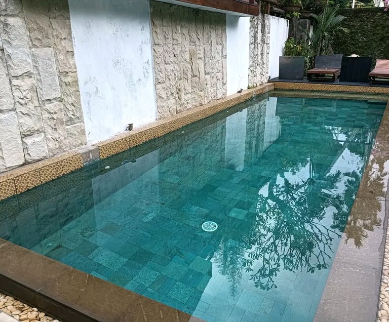 Desain kolam renang minimalis modern dengan air jernih di halaman belakang rumah
