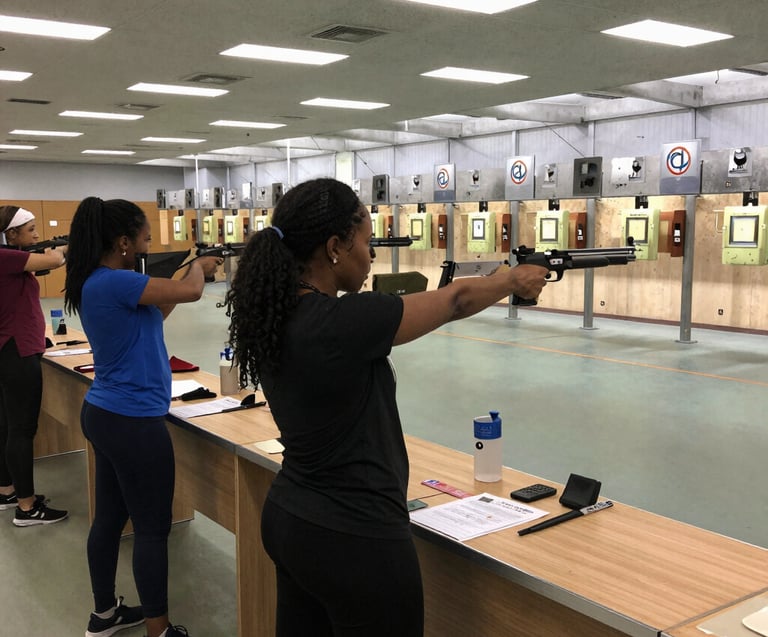 A group of women practicing shooting drills with focused attention and smiles.