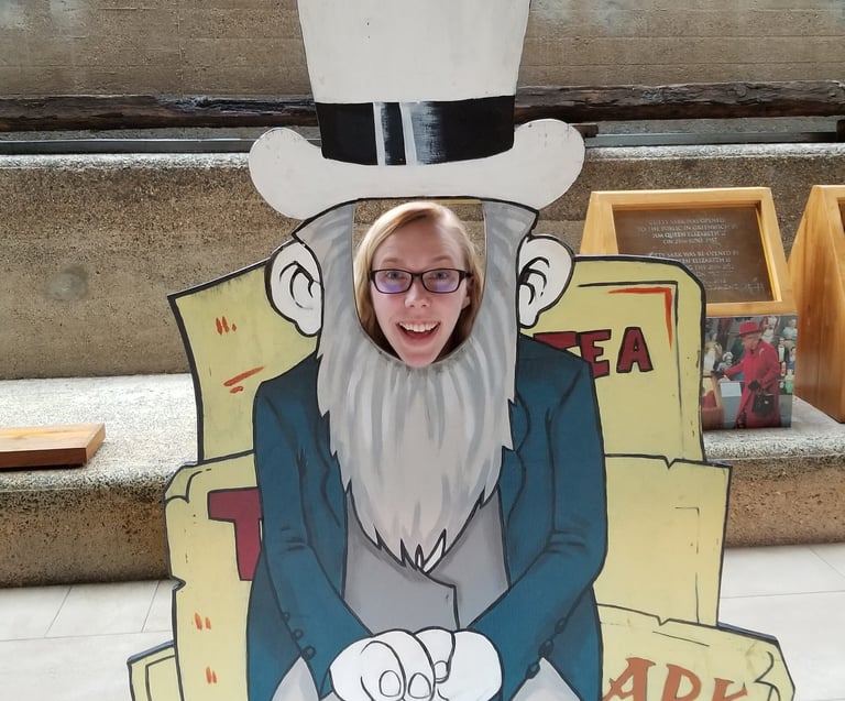 Sarah Schedler, book editor, poses smiling with her face poking through a wooden cut-out.