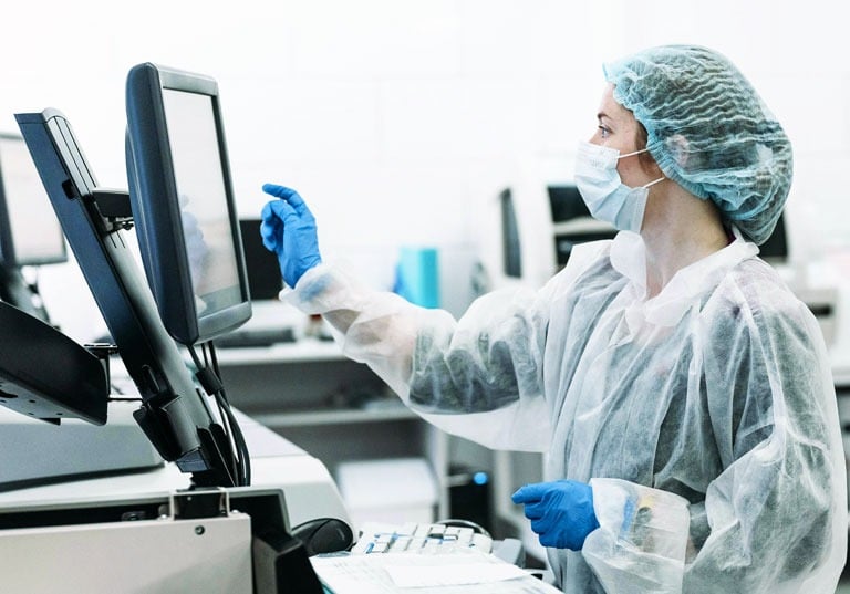 gowned and gloved female doctor interfacing with medical equipment