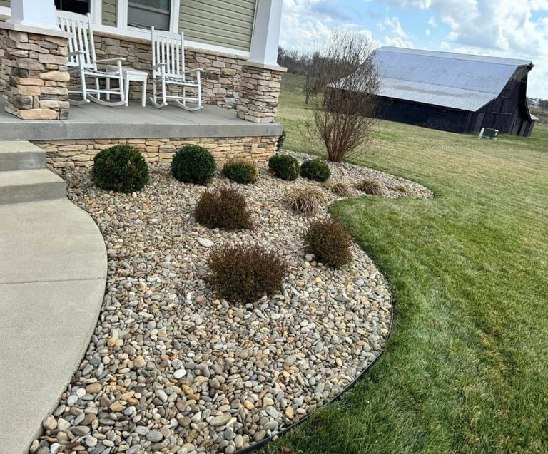 Decorative rock landscaping with shrubs and stonework around a residential home by Valor Home Professionals