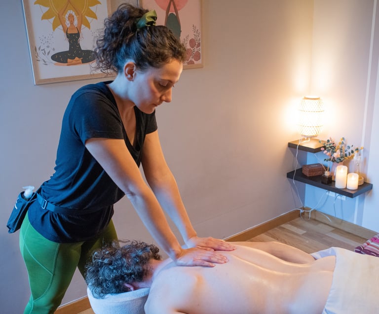 Masseuse bras tendus qui masse le dos d'un client avec bougies et décoration dans la pièce